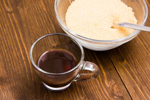 Coffee and bowl with brown sugar on wooden table from above