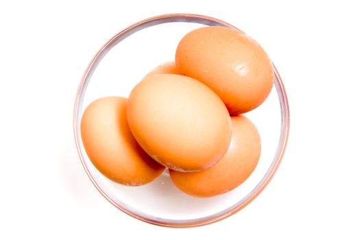 Eggs in glass bowl on white background from above