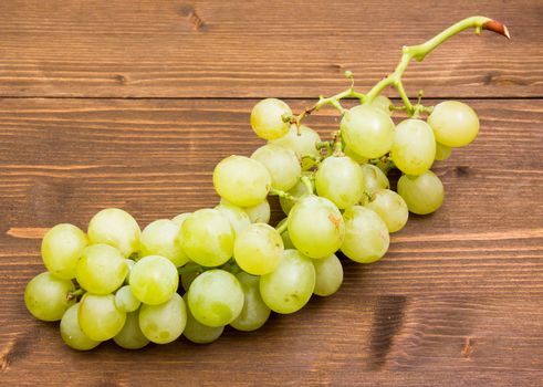 Bunch of grapes on wooden table seen from above