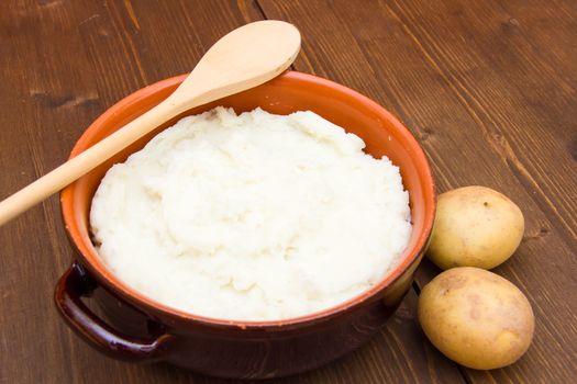 Mashed potato with spoon on wooden table