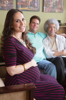 Grinning pregnant surrogate female sitting with happy parents