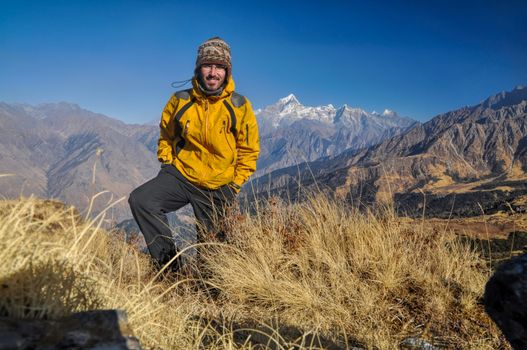 Hiker standing on a hillside in Kuari Pass with breathtaking view of mountains in the background