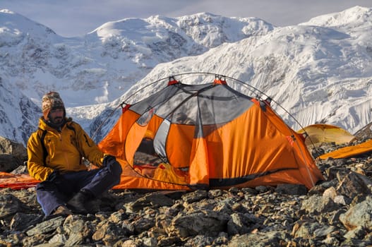 Adventurous hiker camping near Engilchek glacier in scenic Tian Shan mountain range in Kyrgyzstan