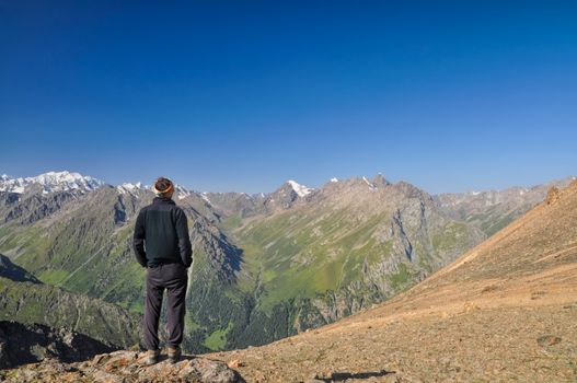 Hiker looking at view of Tien-Shan mountain range in Kyrgyzstan