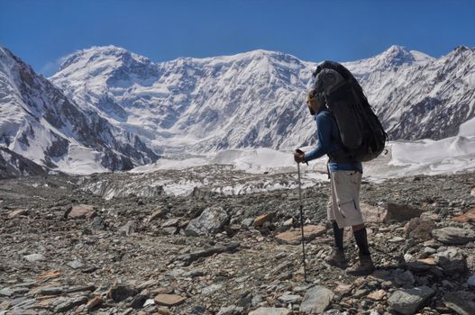 Adventurous hiker with backpack on Engilchek glacier in scenic Tian Shan mountain range in Kyrgyzstan