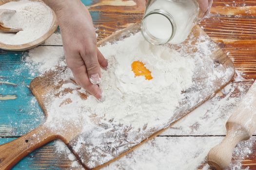 Woman pouring milk into flour as she prepares to bake