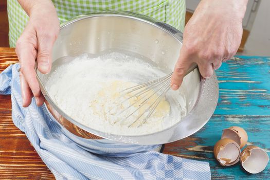 Woman mixing eggs and wheat flour in a bowl.