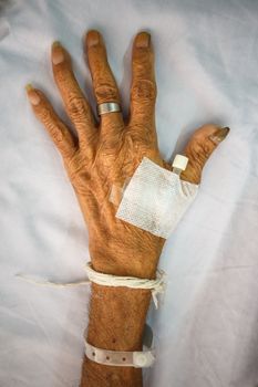 hand of old patient with plug on bed in hospital (vignette style)