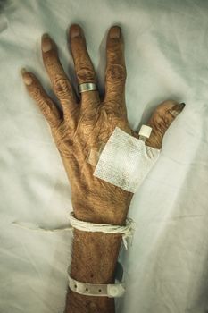 hand of old patient with plug on bed in hospital (vignette style)