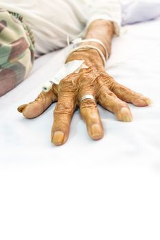 old patient's hand with plug on bed in hospital and blank area at lower side for fill text