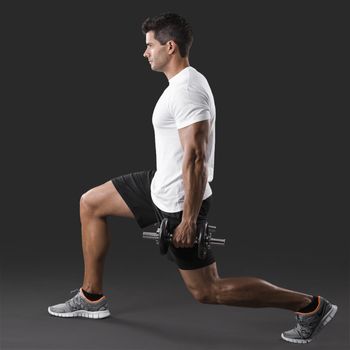 Man making exercise, lifting weight on a grey background 