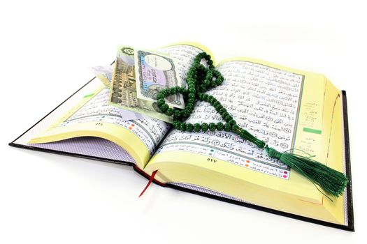 Koran with Egyptian banknotes in front of white background
