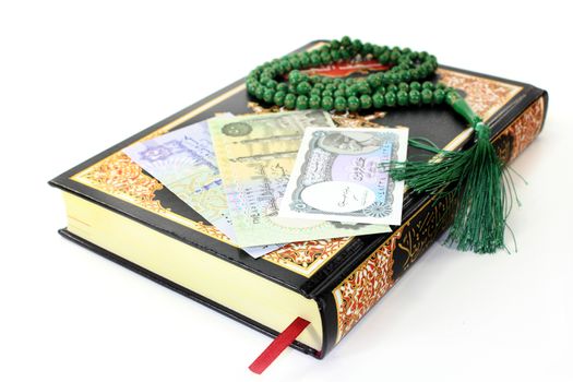 Koran with Egyptian banknotes in front of white background