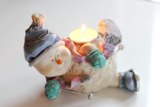Cheerful snowman skier. Candlestick with burning candle