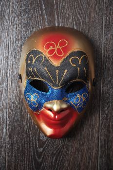 Carnival Venetian mask on a hardwood wall. Vertical photo