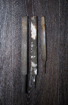 Three old rasps on a wooden surface. Vertical photo