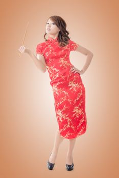 Smiling Chinese woman dress traditional cheongsam standing and holding chopsticks at New Year, full length portrait isolated.