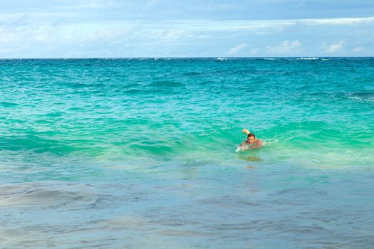 Man swimming alone in the waves body surfing at Bermudas John Smiths Bay beach.