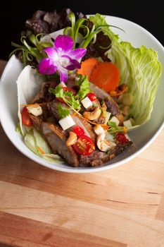 Thai Salad with crispy duck and fresh green mango tomatoes and cashew nuts on a bed of lettuce. Macro detail with shallow depth of field.