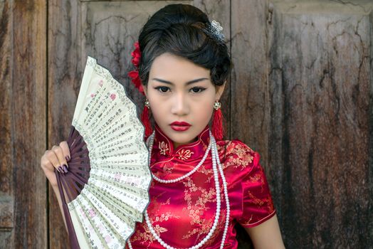 Chinese woman red dress traditional cheongsam ,close up portrait with old wood door