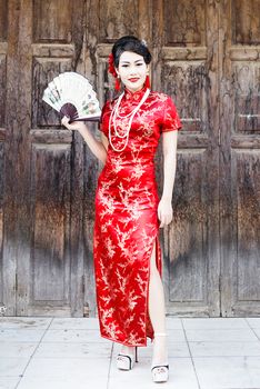 Chinese woman red dress traditional cheongsam ,close up portrait with old wood door