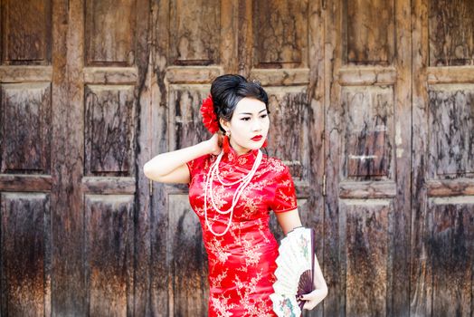 Chinese woman red dress traditional cheongsam ,close up portrait with old wood door