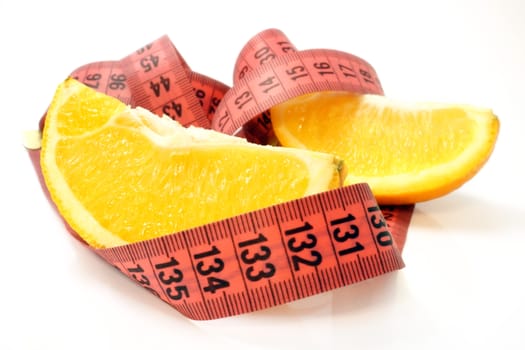 Orange slices with tape measure on white background. Fruit diet concept. Selective focus.