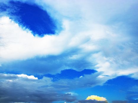 Cloudscape in the midday beautifully arranged in layers with a yellow glow in the far away cloud