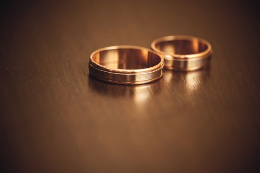 two wedding rings laying on wooden table 