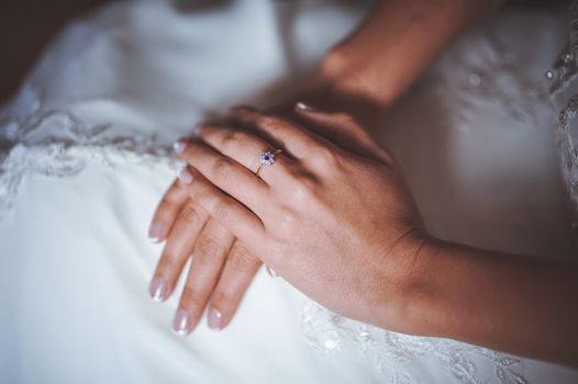 hands of bride with ring crossed on legs