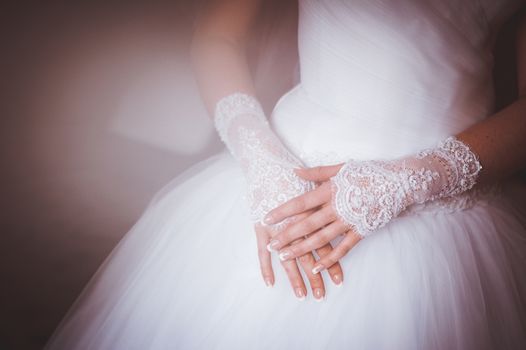 hands of bride in gloves crossed on legs