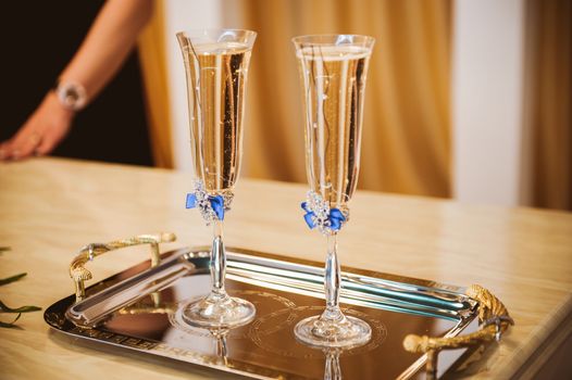 two champagne glasses decorated with blue bow 