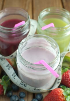 Three flavored smoothies in jars with fruit 