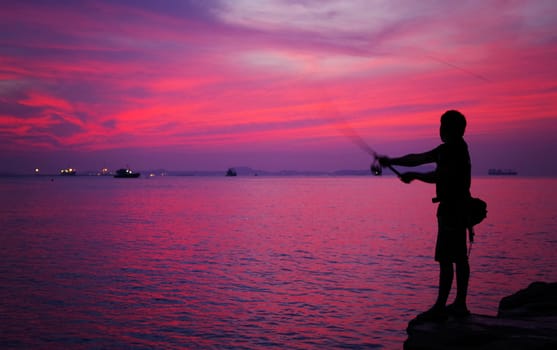 Silhouette of man fishing  beside the sea