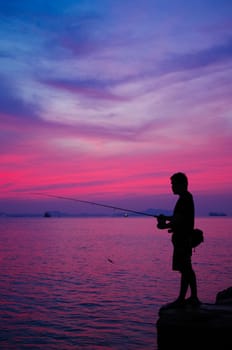 Silhouette of man fishing  beside the sea