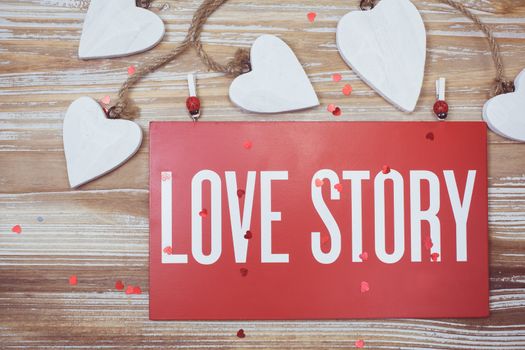 Love story words written on a board, vintage hearts and rustic old wooden background