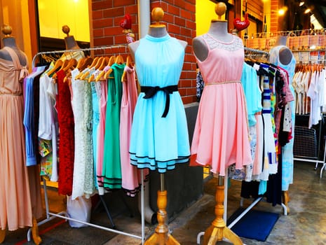 Clothing store hanging clothes women, beautiful colors located in front of the shop.                           