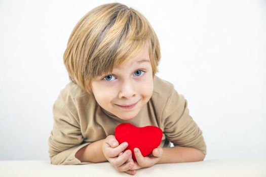 Cute young boy with a red heart in his hands