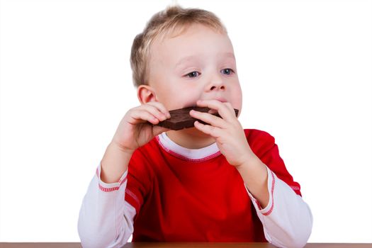 A small boy in red shirt eating whole bar of chocolate. Isolated on white background
