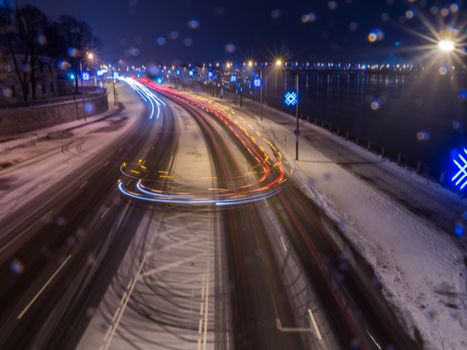 Car light in night on ice road in snow winter, Latvia