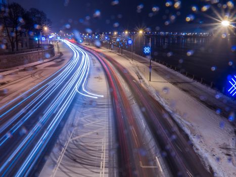 Car light in night on ice road in snow winter, Latvia