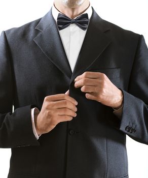 hands of the man who in a black tuxedo clasps a jacket button