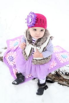 Baby girl sitting outside in the snow