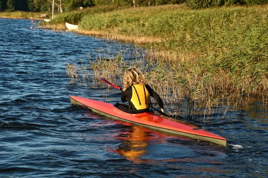 Blond girl on a kayak on a lake in Denmark