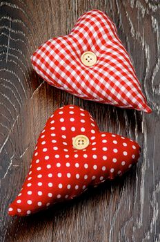 Two Handmade Textile Valentine Red Polka Dot Hearts closeup on Dark Wooden background