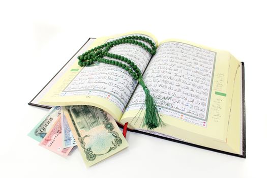 Koran with Afghan banknotes in front of white background