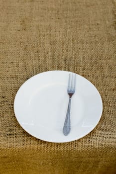 Place setting with plate and fork against brown plate mat