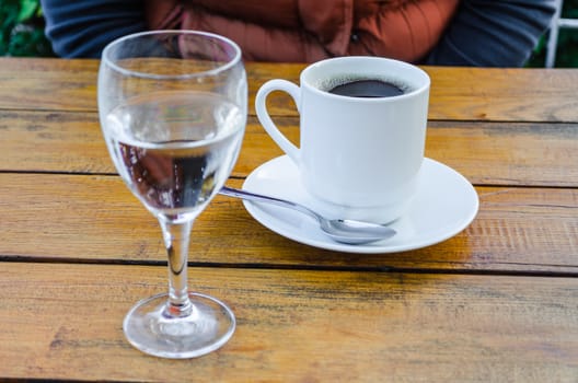 Coffee cup and water glass on a wooden table.