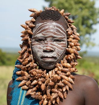 JINKA, ETHIOPIA - NOVEMBER 21, 2014: Young Mursi girl with traditional paintings and necklace on November 21, 2014 in Jinka, Ethiopia.