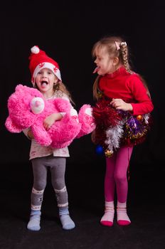 Two girls of five and three years in a New Year dress on a black background